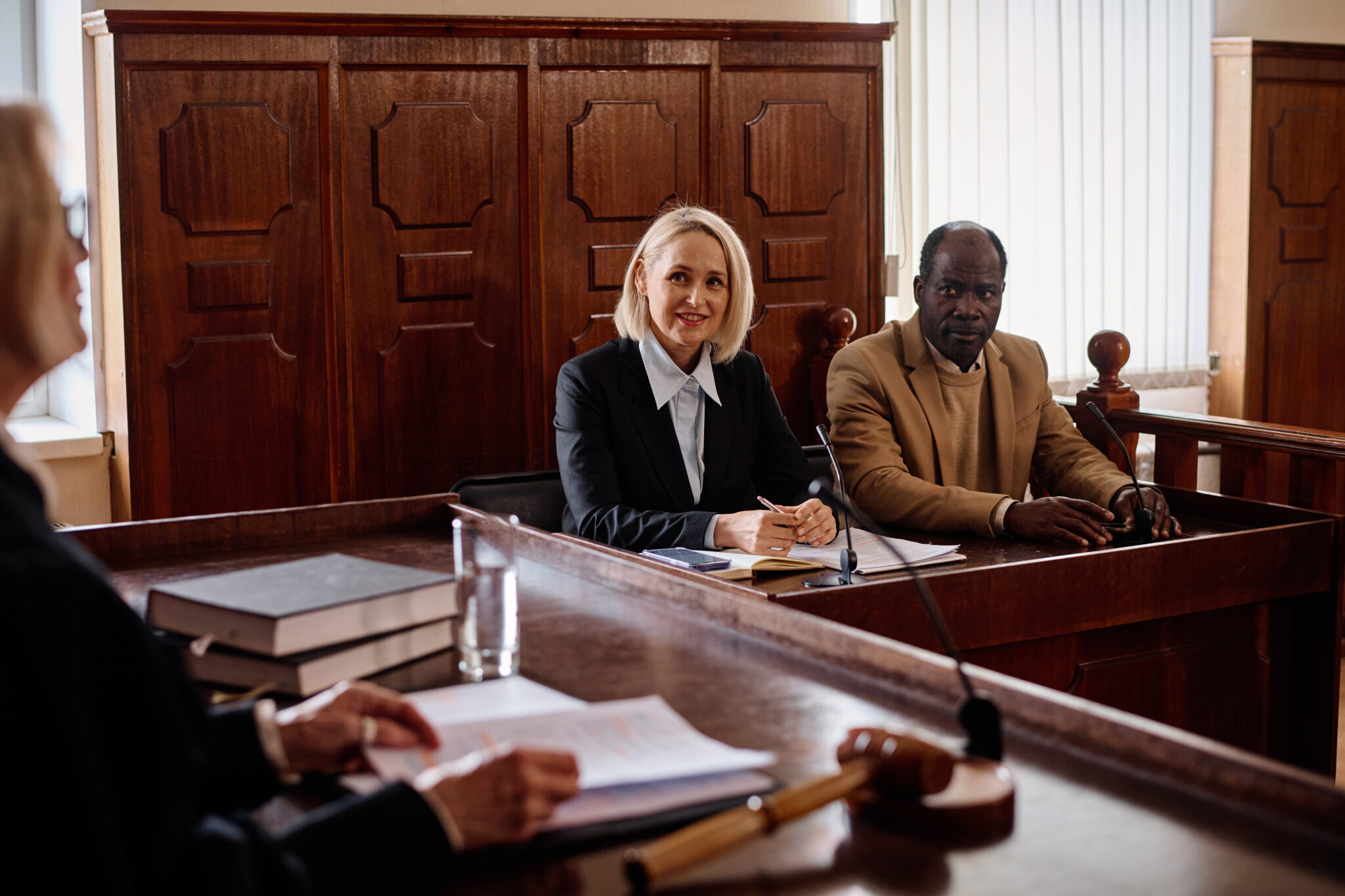 A female lawyer and a male client sitting in a courtroom, engaged in a legal proceeding.