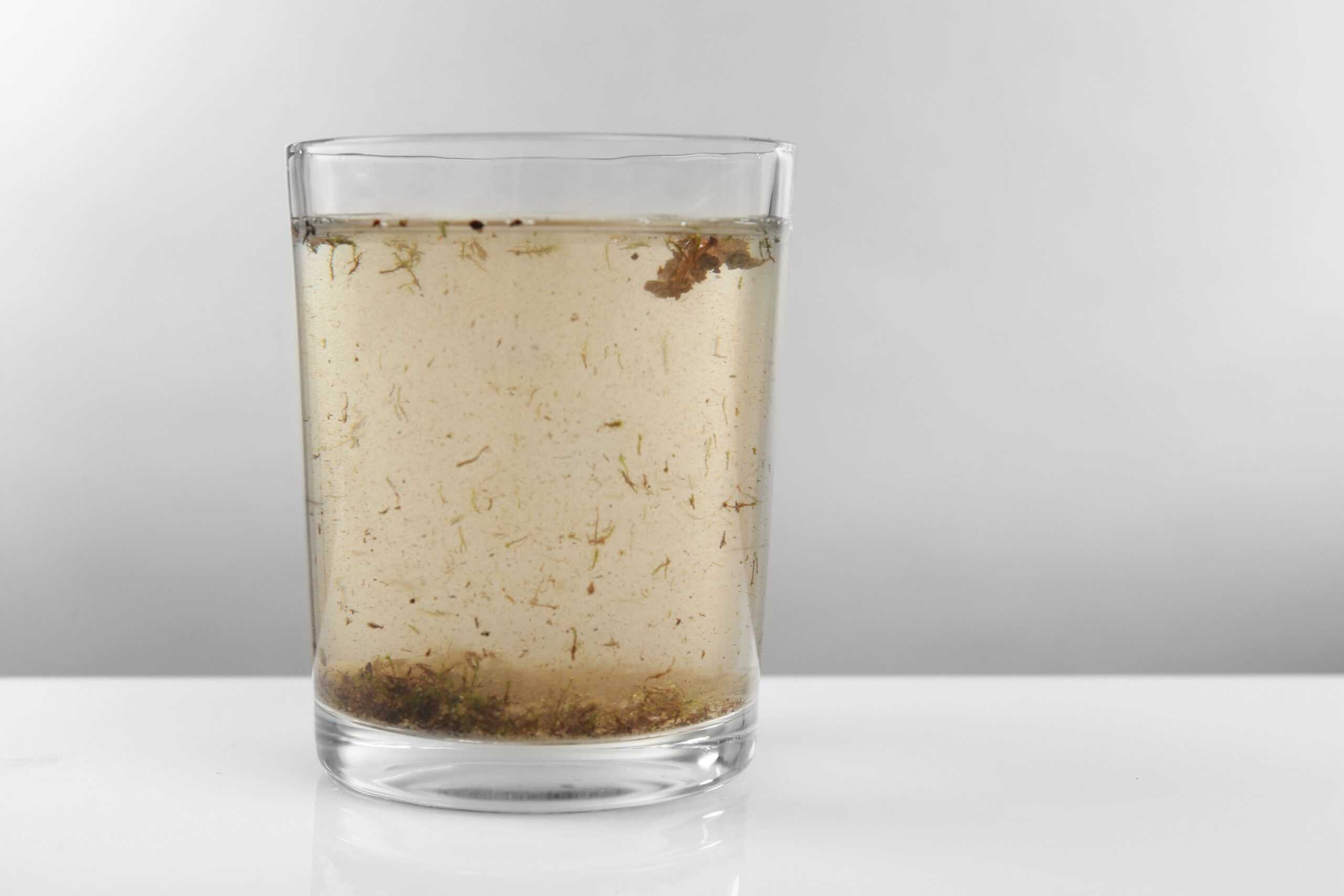 Glass of contaminated, murky water with visible dirt and debris, symbolizing water pollution issues like the Camp Lejeune water contamination lawsuit.
