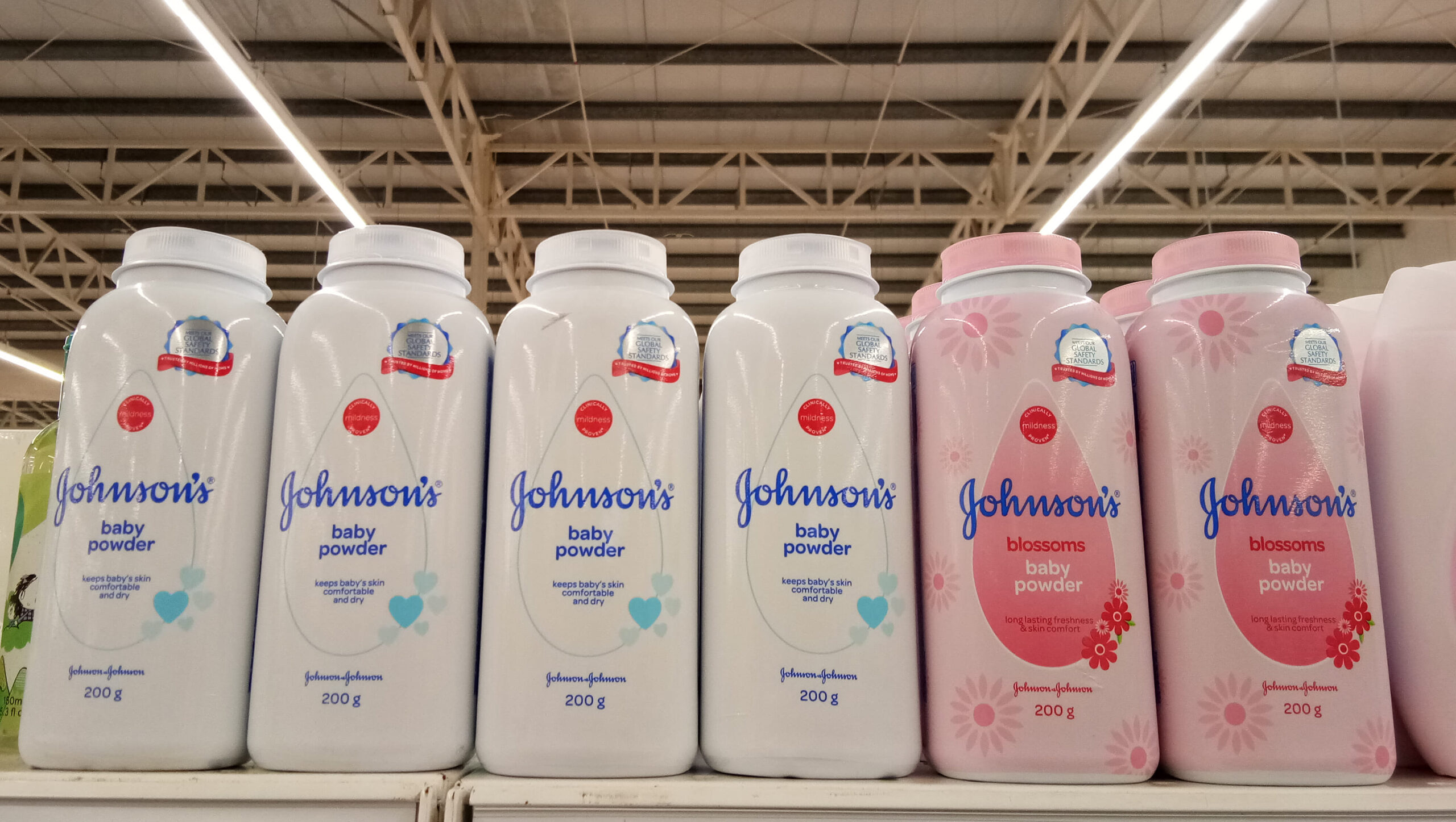 Johnson & Johnson baby powder bottles on a store shelf, associated with lawsuits over asbestos contamination and health risks.